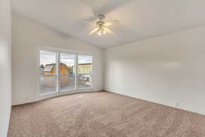 Spare room with carpet flooring, ceiling fan, and vaulted ceiling