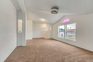 Empty room featuring carpet flooring and vaulted ceiling