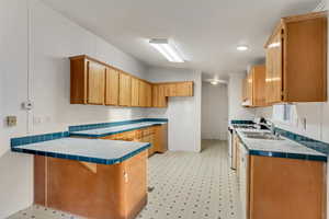 Kitchen featuring kitchen peninsula, tile counters, sink, and white stove