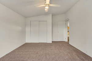 Unfurnished bedroom with carpet flooring, ceiling fan, a closet, and lofted ceiling