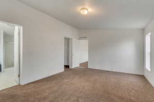 Empty room featuring carpet flooring and vaulted ceiling