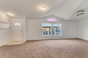 Entrance foyer with carpet floors, a wealth of natural light, and lofted ceiling