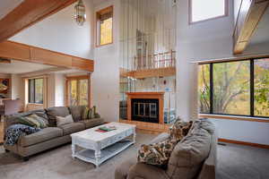 Living room with plenty of natural light, a fireplace, carpet floors, and a high ceiling