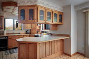 Kitchen featuring electric stove, sink, black dishwasher, light tile patterned flooring, and kitchen peninsula