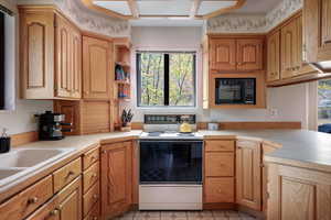 Kitchen with kitchen peninsula, electric range, black microwave, and sink