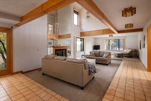 Living room featuring light tile patterned flooring, beam ceiling, and a wealth of natural light