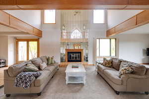 Living room featuring light carpet, a towering ceiling, a tile fireplace, and a wealth of natural light