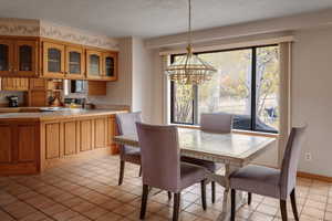 Dining space with light tile patterned flooring, a textured ceiling, and a notable chandelier