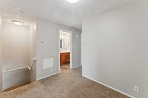 Hallway featuring light carpet and a textured ceiling