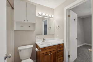 Bathroom featuring vanity, a textured ceiling, and toilet