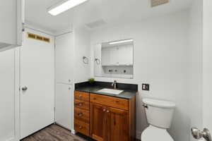 Bathroom featuring vanity, toilet, and wood-type flooring