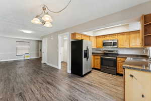 Kitchen featuring sink, hanging light fixtures, stainless steel appliances, a chandelier, and light wood-type flooring