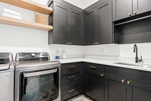 Laundry area with separate washer and dryer, sink, and cabinets