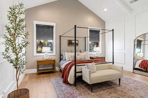 Bedroom featuring wood-type flooring, multiple windows, and vaulted ceiling