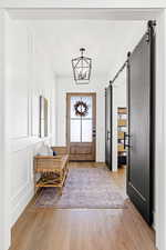 Entryway featuring a barn door, light hardwood / wood-style flooring, and a notable chandelier