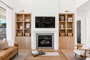 Living room with built in features and light hardwood / wood-style flooring