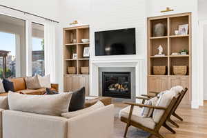 Living room with built in features and light hardwood / wood-style floors