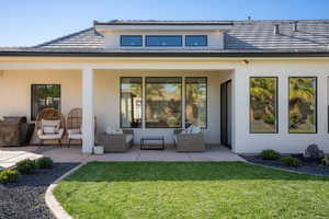 Rear view of house featuring an outdoor living space, a patio, and a lawn