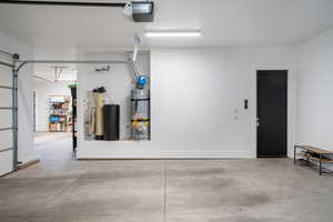 Garage featuring strapped water heater and a garage door opener