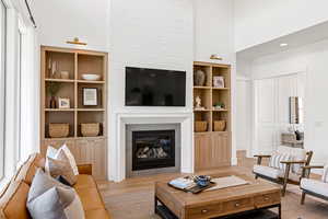 Living room featuring light wood-type flooring, built in features, and a towering ceiling