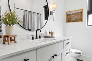 Bathroom featuring a shower with curtain, vanity, and toilet