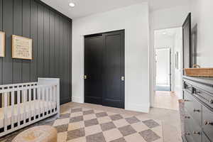 Carpeted bedroom featuring a crib and a closet