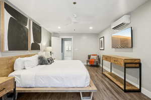 Bedroom with hardwood / wood-style flooring, a wall unit AC, and ceiling fan