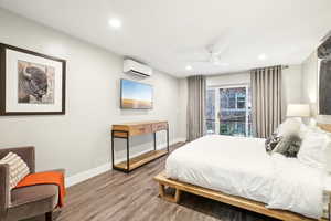 Bedroom featuring a wall unit AC, ceiling fan, and wood-type flooring