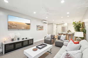 Living room featuring a wall mounted AC and ceiling fan