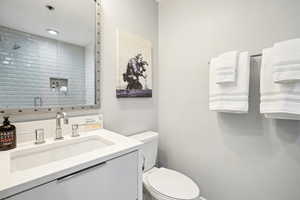 Bathroom featuring vanity, toilet, and a tile shower