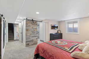 Bedroom featuring a barn door and light carpet