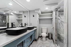 Bathroom featuring vanity, toilet, and a shower with shower door