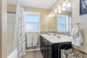 Bathroom featuring shower / tub combo with curtain, vanity, a wealth of natural light, and tasteful backsplash