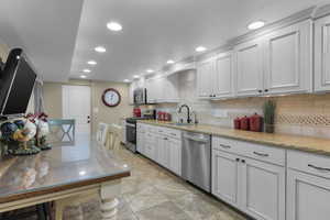 Downstairs Kitchen with appliances with stainless steel finishes, tasteful backsplash, white cabinetry, and sink