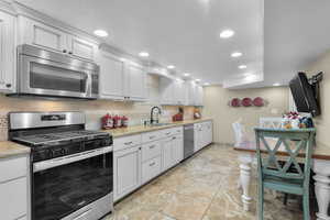 Kitchen downstairs featuring white cabinets, sink, appliances with stainless steel finishes, and tasteful backsplash