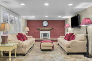 Downstairs family room with a fireplace and brick wall