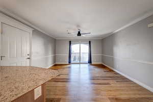 Interior space with hardwood / wood-style floors, ceiling fan, and ornamental molding