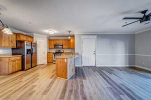 Kitchen with ceiling fan, sink, hanging light fixtures, stainless steel appliances, and crown molding