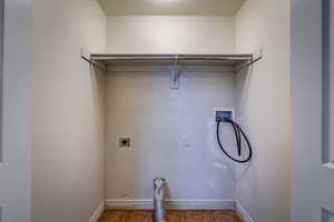 Washroom featuring electric dryer hookup, hookup for a washing machine, and dark tile patterned floors