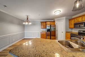 Kitchen with ornamental molding, sink, a chandelier, and appliances with stainless steel finishes