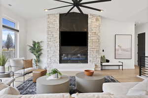 Living room featuring light hardwood floors, vaulted ceiling, and a fireplace