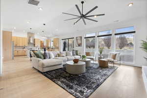 Living room with light hardwood flooring, vaulted ceiling, and ceiling fan