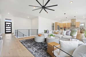 Living room featuring ceiling fan, light hardwood flooring, and vaulted ceiling