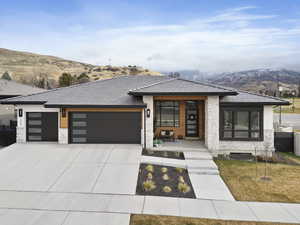 Modern home with a mountain view, a garage, a front lawn, and covered porch