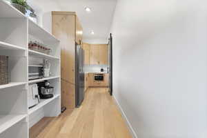 Butlers pantry with a barn door and light hardwood / wood-style flooring