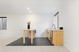 Kitchenette, light brown cabinetry, sink, mini fridge.