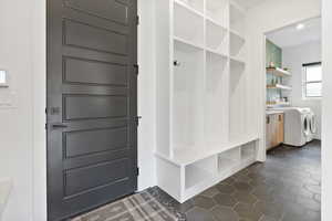 Mudroom with separate washer and dryer and dark tile patterned flooring