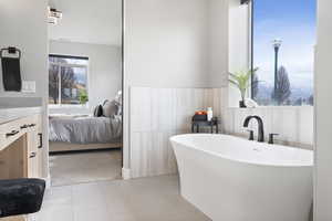 Primary bathroom featuring tile patterned floors, a free standing tub, and double vanity with quartz counter tops.