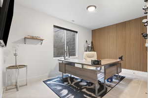 Basement bedroom/Office area with wood accent wall and light colored carpet.