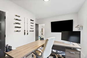 Basement bedroom/Office area with wood accent wall and light colored carpet.